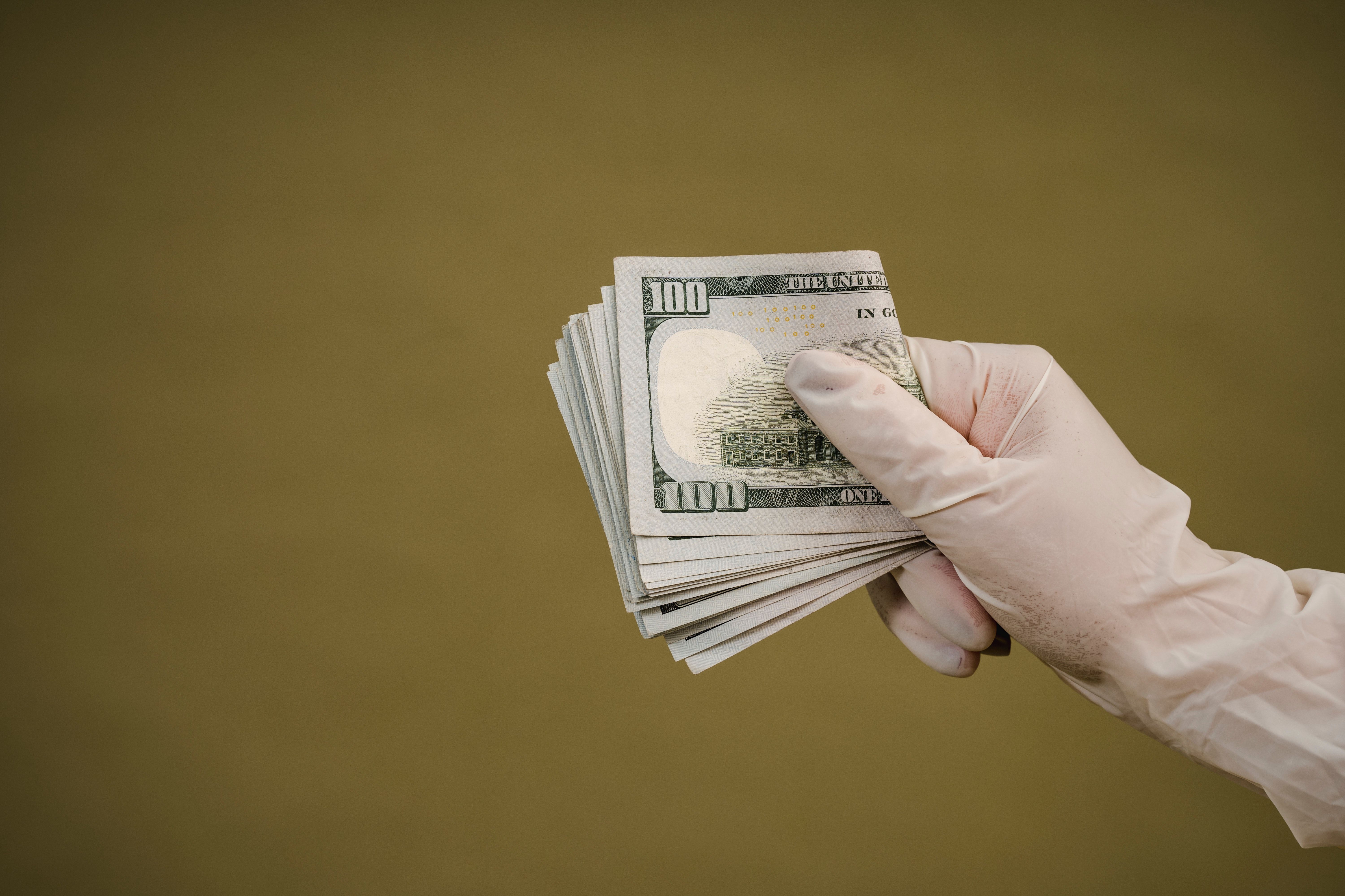 Hand holding wad of 100 dollar bills